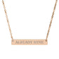 Rose gold bar necklace with engraved uppercase text "ALREADY MINE" on a sleek matte pendant, suspended on a delicate matching rose gold chain. Minimalist motivational affirmation jewelry for self-ownership, confidence, and empowerment.
