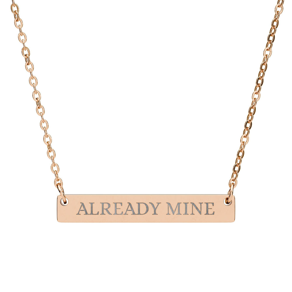 Rose gold bar necklace with engraved uppercase text "ALREADY MINE" on a sleek matte pendant, suspended on a delicate matching rose gold chain. Minimalist motivational affirmation jewelry for self-ownership, confidence, and empowerment.