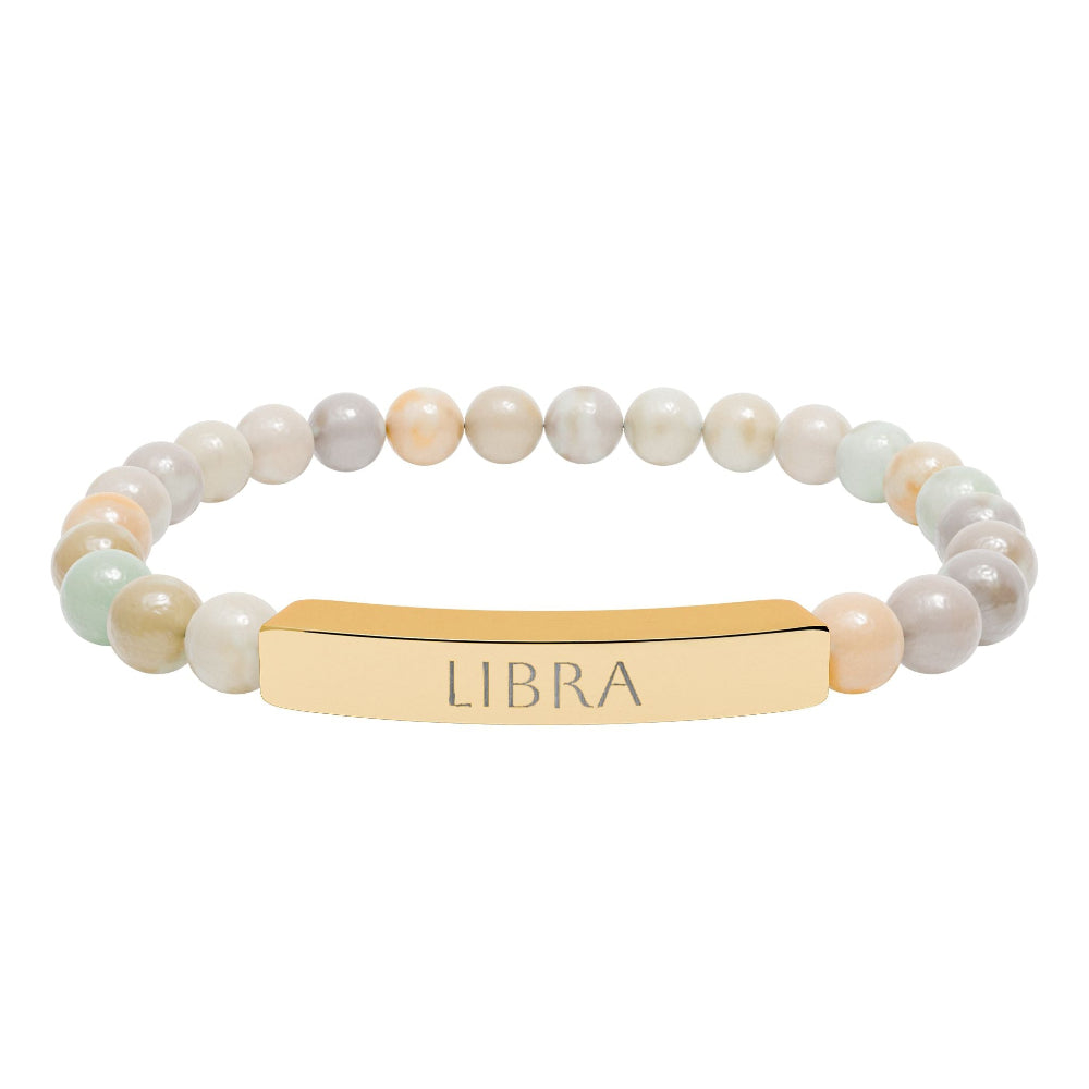 Bracelet with polished pastel beads in soft peach, cream, gray, and light blue tones with natural marbling, featuring a gold-plated curved bar engraved "LIBRA" in uppercase letters. Stretch-fit zodiac-inspired crystal jewelry for balance, harmony, and relationships.