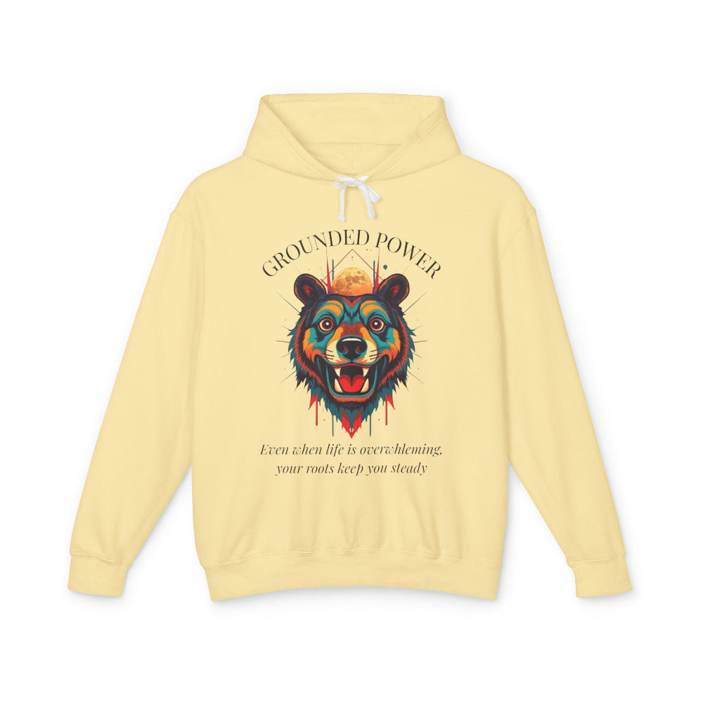 Light yellow hoodie with vibrant multicolored bear head graphic, roaring expression, fur in blue orange teal splashes, full moon above, "GROUNDED POWER" arched text, motivational quote "Even when life is overwhelming, your roots keep you steady" below