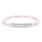 Bracelet with polished rose quartz beads in soft pink tones and natural translucent glow, paired with a silver curved bar engraved "SAGITTARIUS" in uppercase letters. Stretch-fit zodiac-inspired crystal jewelry.