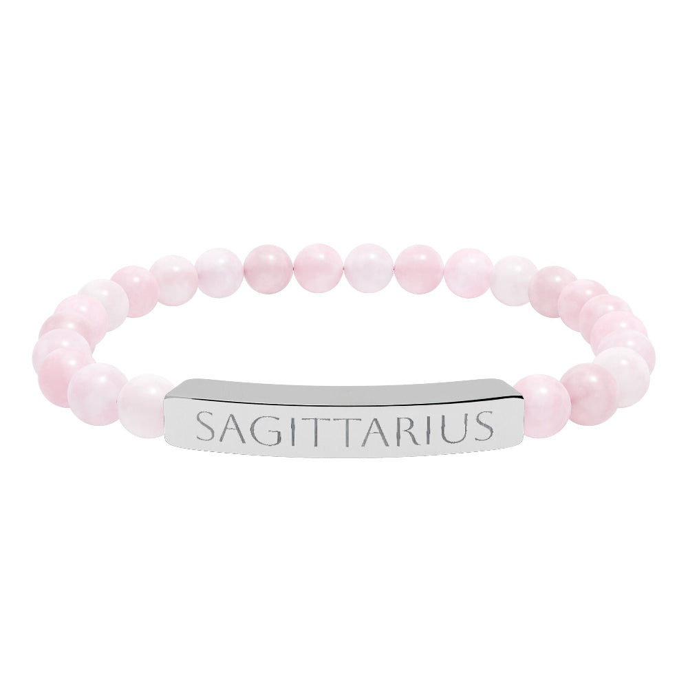 Bracelet with polished rose quartz beads in soft pink tones and natural translucent glow, paired with a silver curved bar engraved "SAGITTARIUS" in uppercase letters. Stretch-fit zodiac-inspired crystal jewelry.