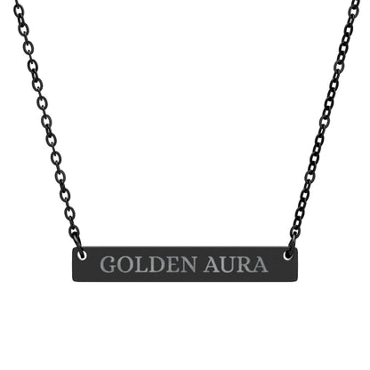 Black bar necklace with engraved uppercase text "GOLDEN AURA" on a matte black pendant, suspended on a delicate black chain. Minimalist motivational affirmation jewelry for radiance, positivity, and energetic glow.