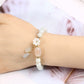 White jade beaded bracelet worn on wrist with gold plum blossom charm, translucent agate focal bead, and dangling jade-amethyst teardrop pendants