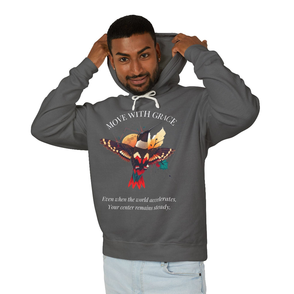 Man modeling a charcoal grey hoodie with 'Move With Grace' inspirational hummingbird graphic and quote 'Even when the world accelerates, Your center remains steady' printed on the front.