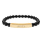 Bracelet with polished black onyx beads and gold-plated curved bar engraved "ARIES" in uppercase letters. Stretch-fit zodiac-inspired crystal jewelry.