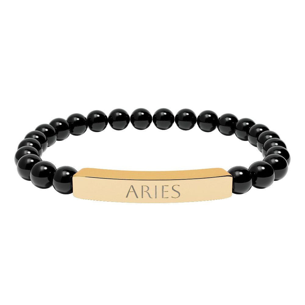 Bracelet with polished black onyx beads and gold-plated curved bar engraved "ARIES" in uppercase letters. Stretch-fit zodiac-inspired crystal jewelry.