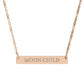 Rose gold bar necklace with engraved uppercase text "MOON CHILD" on a sleek matte pendant, suspended on a delicate matching rose gold chain. Minimalist spiritual affirmation jewelry for lunar energy, intuition, and cosmic connection.