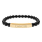 Bracelet with polished black onyx beads and gold-plated curved bar engraved "CANCER" in uppercase letters. Stretch-fit zodiac-inspired crystal jewelry.