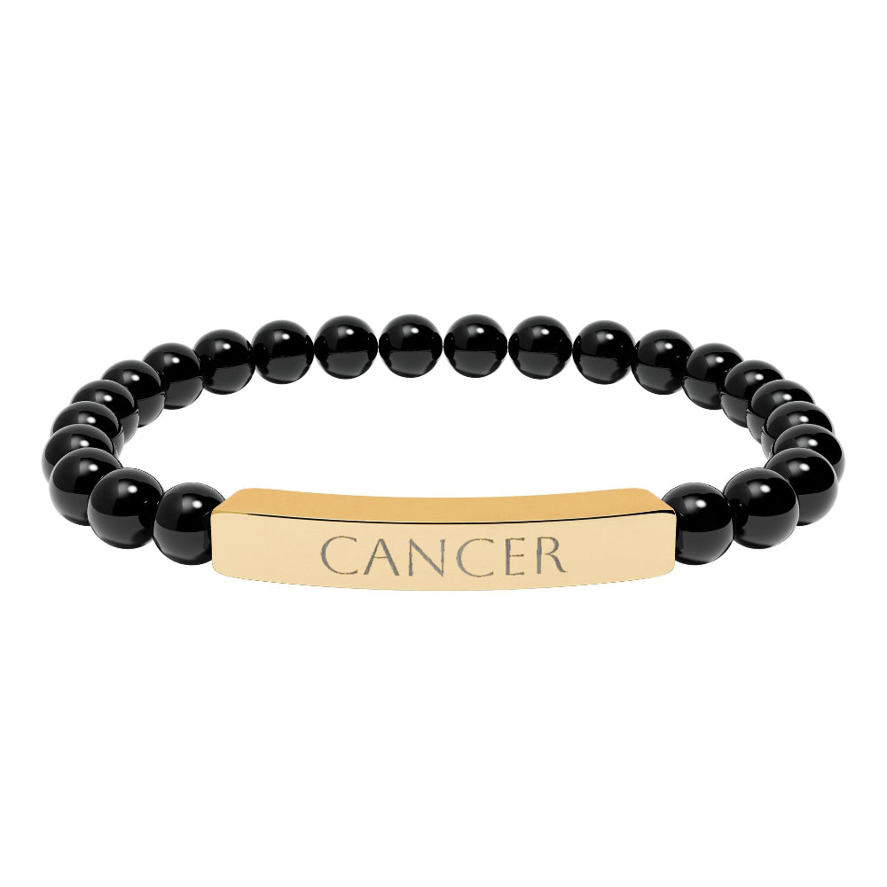 Bracelet with polished black onyx beads and gold-plated curved bar engraved "CANCER" in uppercase letters. Stretch-fit zodiac-inspired crystal jewelry.