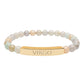 Bracelet with polished pastel beads in soft peach, cream, gray, and light blue tones with natural marbling, featuring a gold-plated curved bar engraved "VIRGO" in uppercase letters. Stretch-fit zodiac-inspired crystal jewelry.
