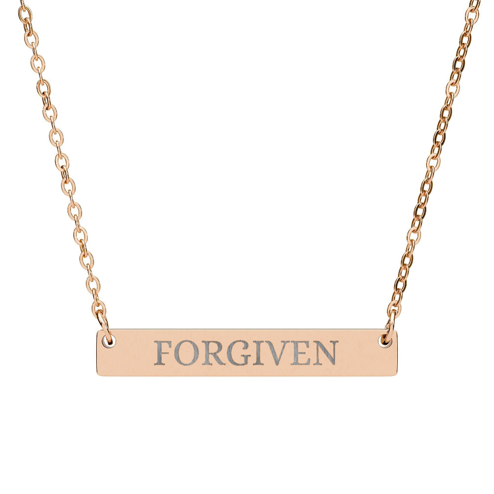 Rose gold bar necklace with engraved uppercase text "FORGIVEN" on a sleek matte pendant, suspended on a delicate matching rose gold chain. Minimalist motivational affirmation jewelry for forgiveness, healing, and emotional release.