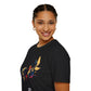 Black unisex cotton t-shirt in side profile on smiling woman with braided hair, featuring bold Pisces zodiac graphic on chest: vibrant abstract twin goldfish swimming in mirrored formation, detailed scales and flowing fins, intense eyes, geometric accents, and dynamic multicolored paint splatters in gold, red, navy, teal, blue, and black tones bursting outward. Elegant black cursive "Pisces" text below. Astrology zodiac motivational crewneck tee.