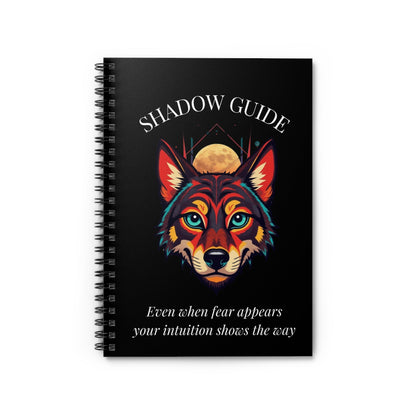 Close up of notebook with a colorful abstract wolf head portrait, intense turquoise eyes, geometric accents, and paint splatters on a black background, featuring the words "SHADOW GUIDE" and quote "Even when fear appears, your intuition shows the way".