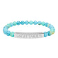 Bracelet with polished turquoise beads in soft aqua-blue tones with natural veining and speckles, featuring a silver curved bar engraved "SAGITTARIUS" in uppercase letters. Stretch-fit zodiac-inspired crystal jewelry.
