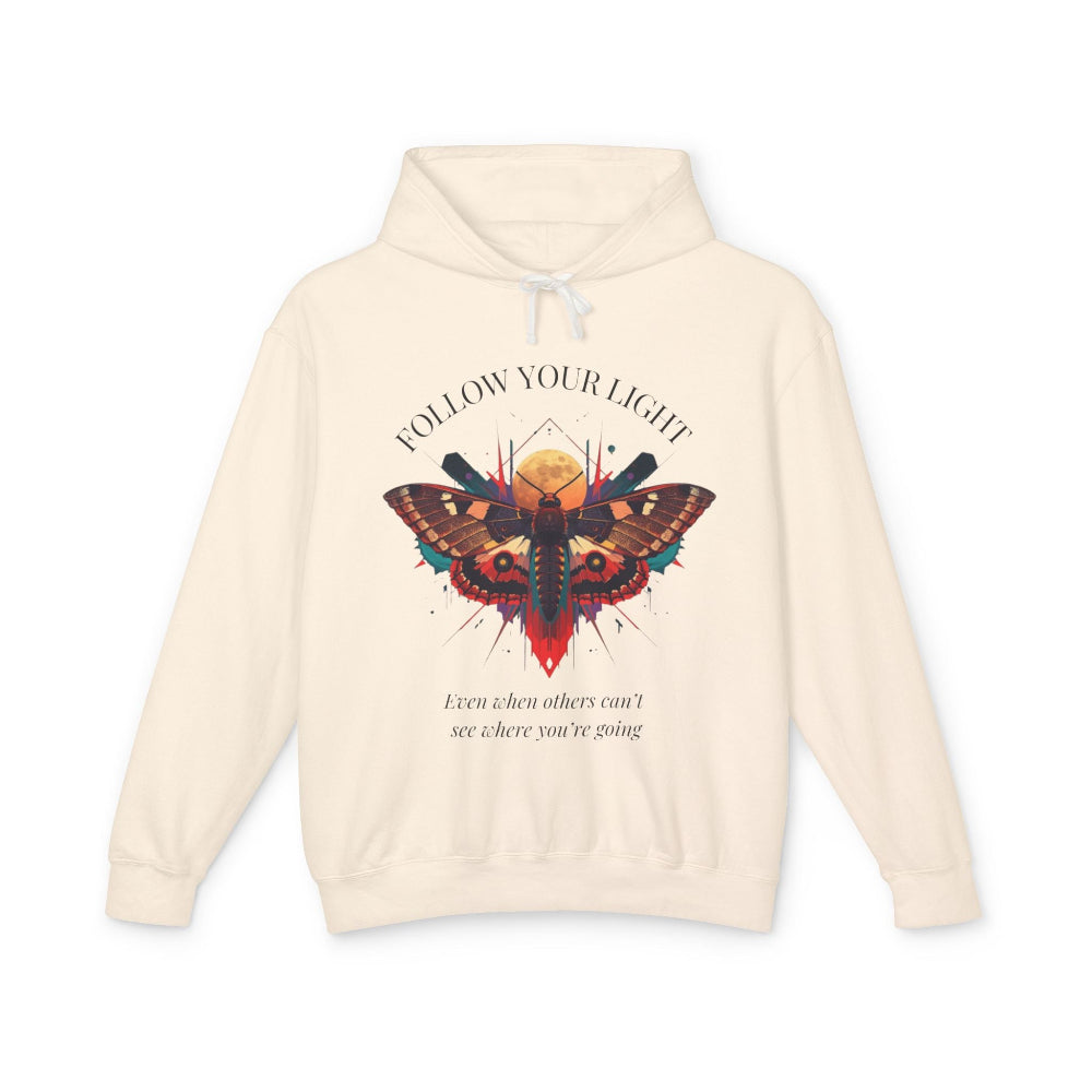 Cream hoodie with vibrant multicolored moth/butterfly graphic, geometric sun/moon elements, "FOLLOW YOUR LIGHT" arched text above, motivational quote "Even when others can't see where you're going" below