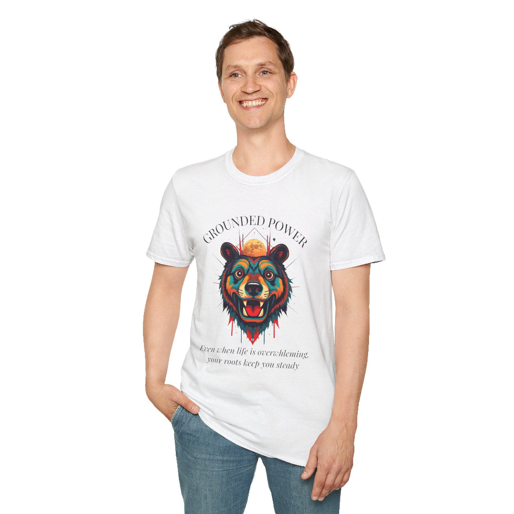 White unisex cotton t-shirt modeled by smiling man with short brown hair, featuring bold "Grounded Power" graphic: vibrant abstract bear head portrait with intense expression, colorful geometric accents, and dynamic paint splatters in red, orange, teal, blue, and gold around an orange moon. Arched white text "GROUNDED POWER" above and smaller quote "Even when life is overwhelming, your roots keep you steady" below. Motivational spiritual empowerment crewneck tee.