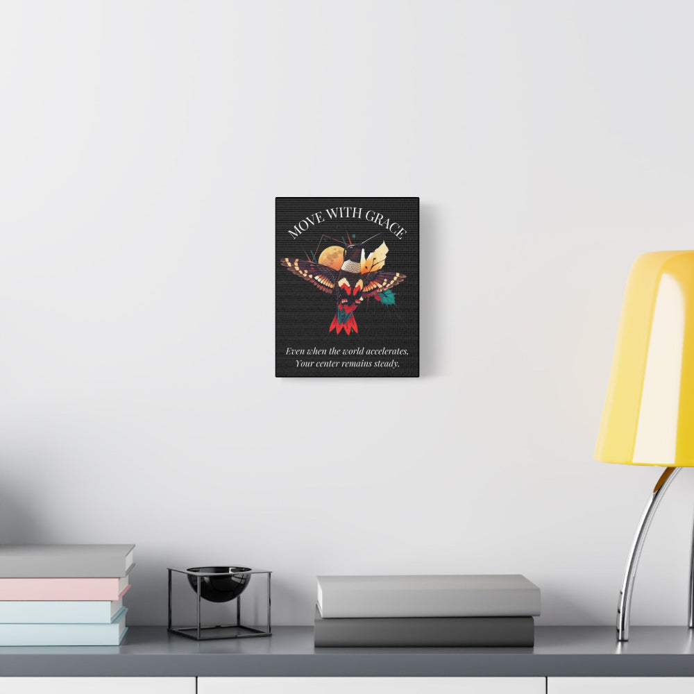 Motivational 'Move With Grace' hummingbird canvas wall art displayed in a bright, minimalist interior with white walls, console table decor, and a yellow lamp.