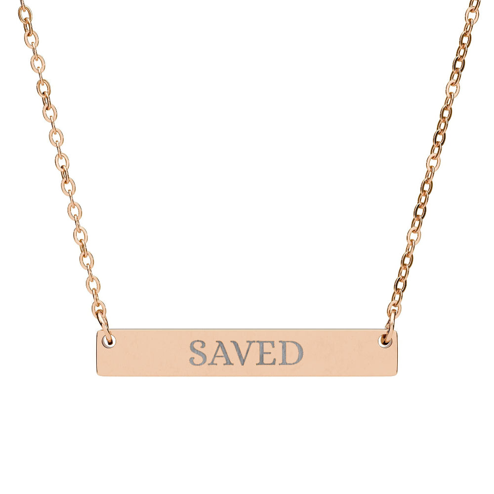 Rose gold bar necklace with engraved uppercase text "SAVED" on a sleek matte pendant, suspended on a delicate matching rose gold chain. Minimalist motivational affirmation jewelry for grace, redemption, and spiritual protection.