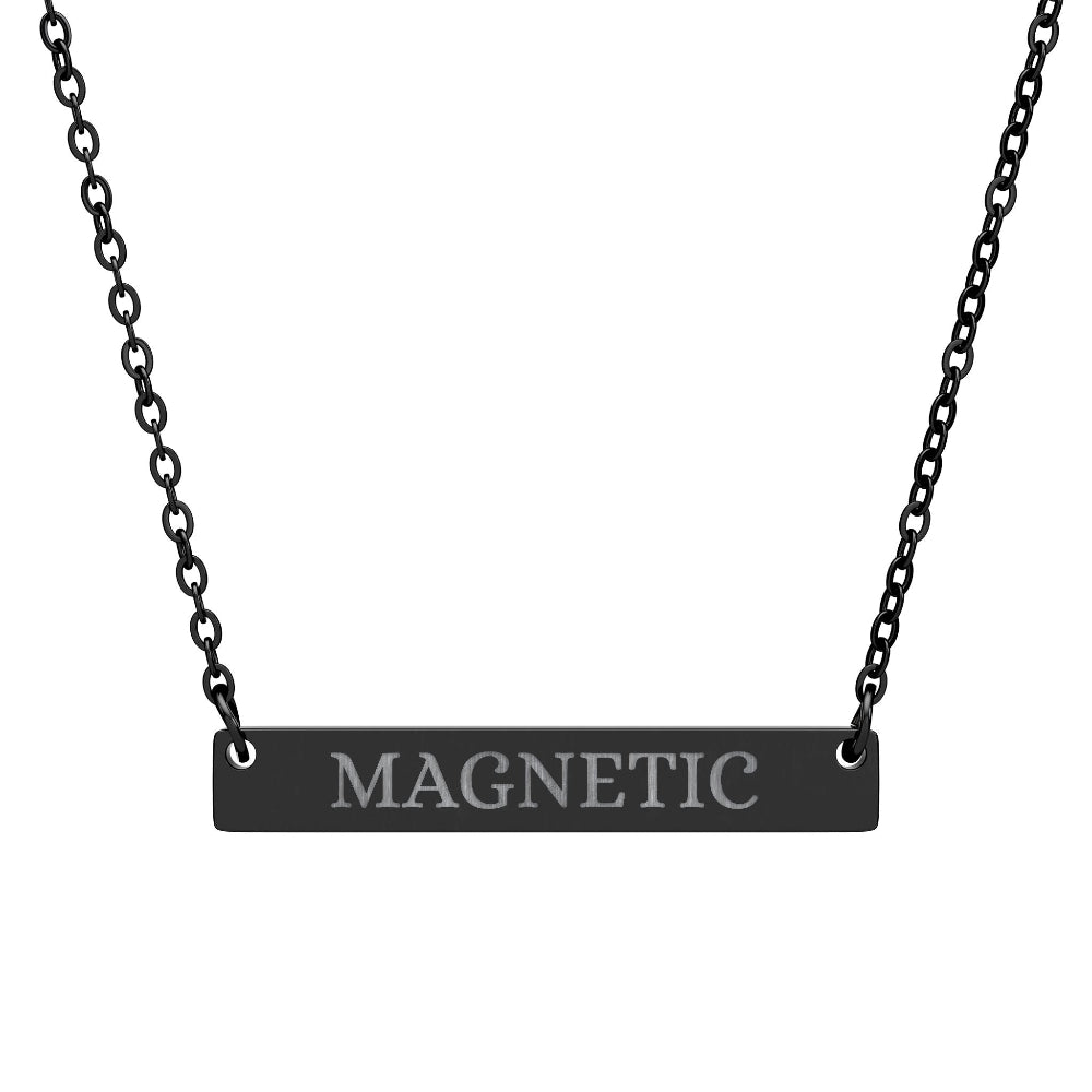 Black bar necklace with engraved uppercase text "MAGNETIC" on a matte black pendant, suspended on a delicate black chain. Minimalist motivational affirmation jewelry for attraction, charisma, and positive energy.