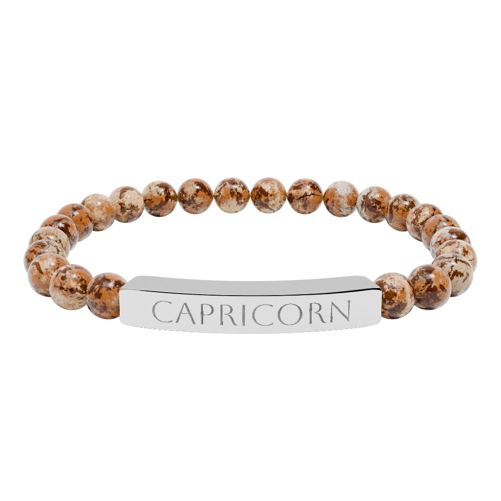 Bracelet with polished leopard jasper beads in earthy brown tones with natural veining, featuring a silver curved bar engraved "CAPRICORN" in uppercase letters. Stretch-fit zodiac-inspired crystal jewelry.