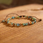 Turquoise and mixed gemstone wrap bracelet: faceted round beads in earthy turquoise, brown, orange, and green tones with natural veining, gold spacers, adjustable brown cord tie closure, displayed on wooden background. Boho handmade crystal jewelry for grounding and protection.