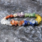 7-chakra healing crystal stretch bracelet – tumbled gemstone nuggets in rainbow order: red jasper, carnelian, citrine, green aventurine, lapis lazuli, amethyst, clear quartz, natural chip beads on elastic cord, displayed on dark textured surface