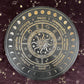 Black and gold Wheel of the Year divination board featuring a central sun and moon design surrounded by zodiac symbols, sabbat names (Yule, Imbolc, Ostara, Beltane, Litha, Lammas, Mabon, Samhain), and moon phase markers. Pagan seasonal wheel on a dark velvet background with gold stars.