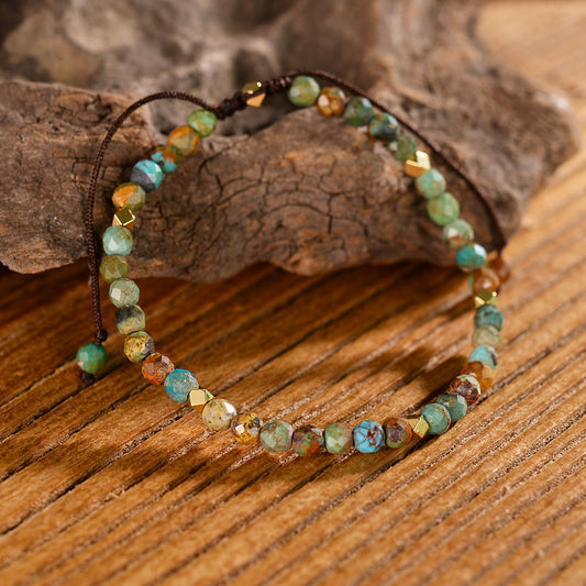 Turquoise and mixed gemstone wrap bracelet: faceted round beads in earthy turquoise, brown, orange, and green tones with natural veining, gold spacers, adjustable brown cord tie closure, displayed on wooden background. Boho handmade crystal jewelry for grounding and protection.