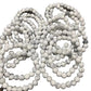 Multiple strands of white howlite round gemstone beads with natural gray marble veining, polished beads arranged on a white background.